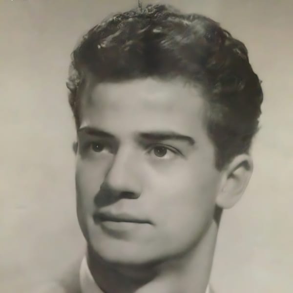 Black and white portrait of a young man with dark, wavy hair looking to the right.