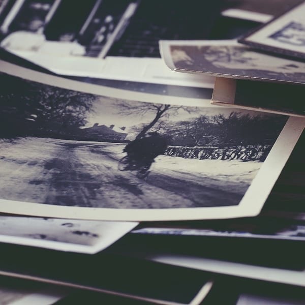 A stack of old, black and white photographs, with a winter scene visible on top.
