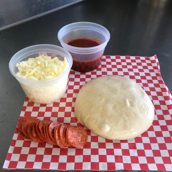 Original Brothers Pizza ingredients: pepperoni, pizza dough, shredded cheese, and tomato sauce on a checkered paper.